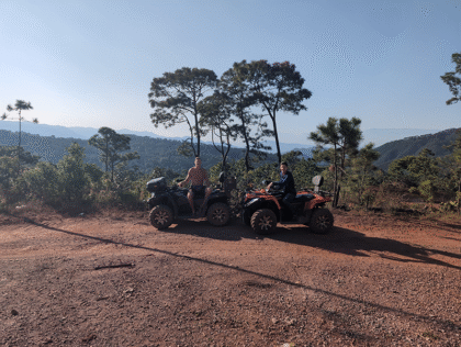 Two people on ATVs in scenic mountains.